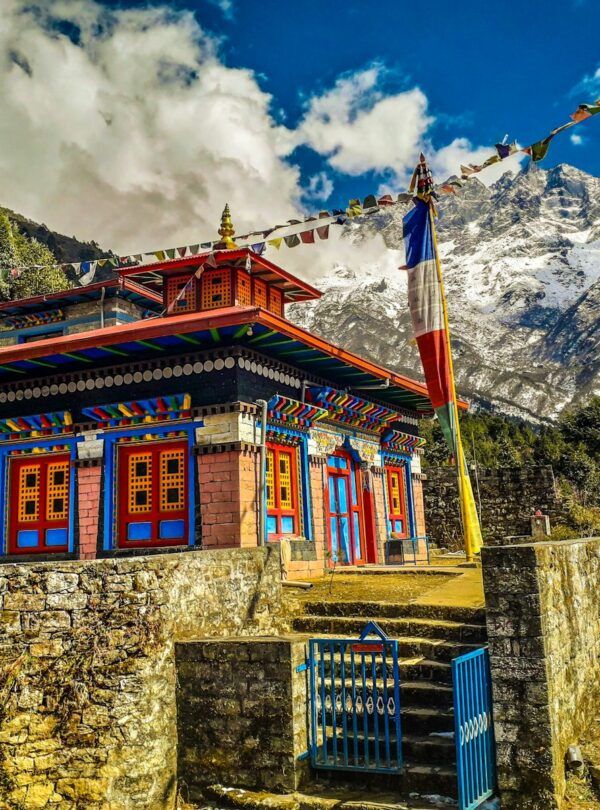 brown and white concrete building near mountain under white clouds and blue sky during daytime