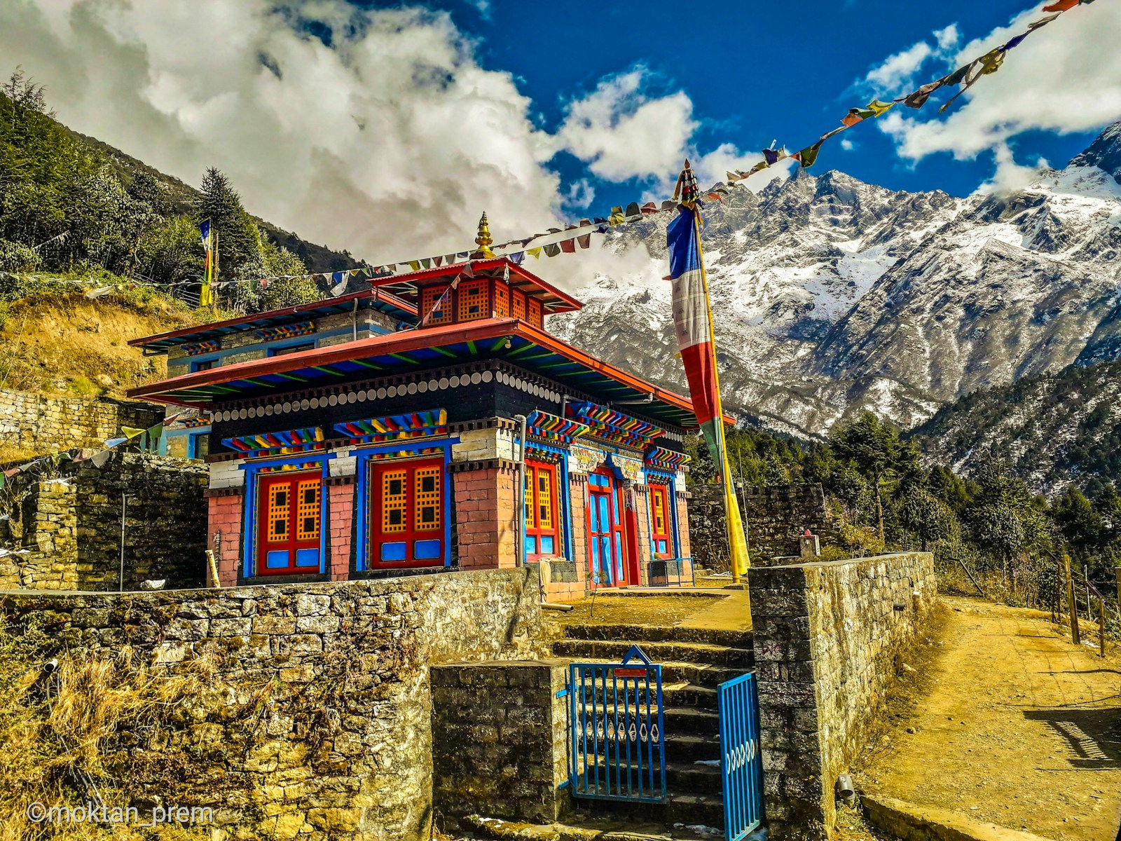 brown and white concrete building near mountain under white clouds and blue sky during daytime